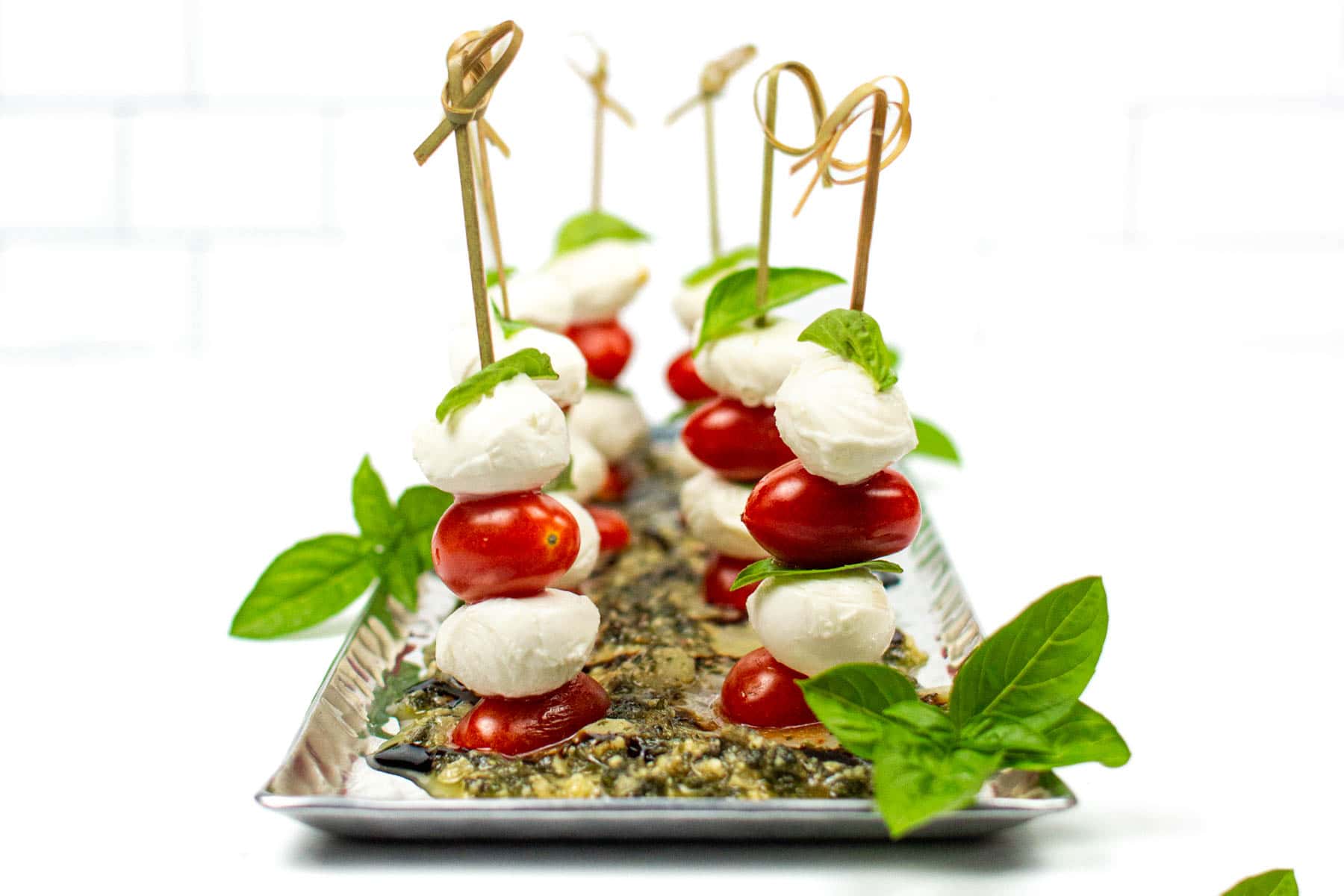 Skewers layered with tomatoes, mozzarella, and basil leaves.