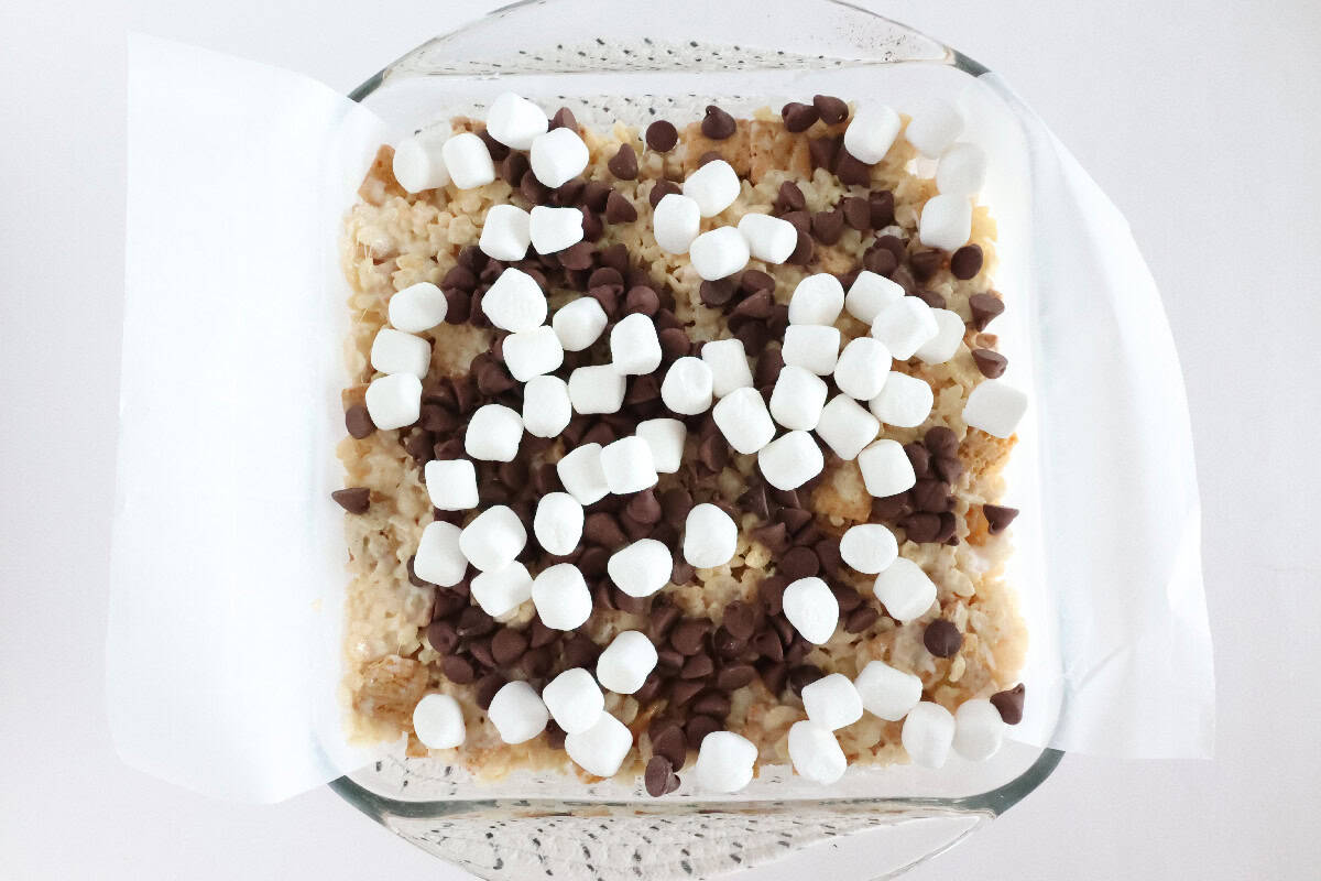 Chocolate chips and mini marshmallows sprinkled over S'mores Rice Krispie treats before setting.