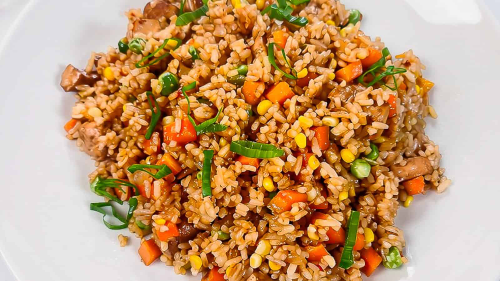 Close-up of vegan nasi goreng made with rice, tofu, carrots, peas, corn, mushrooms, and green onions.