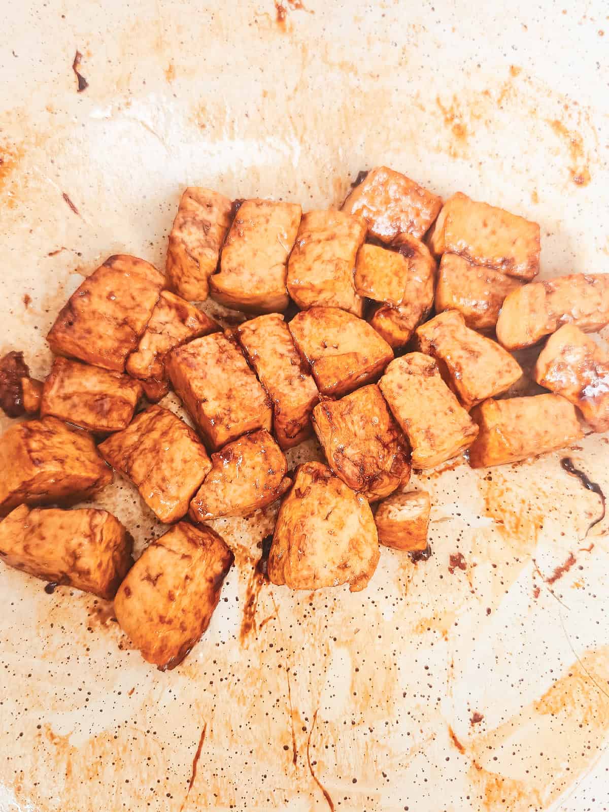 Tofu browned and caramelized in a skillet for vegan nasi goreng.