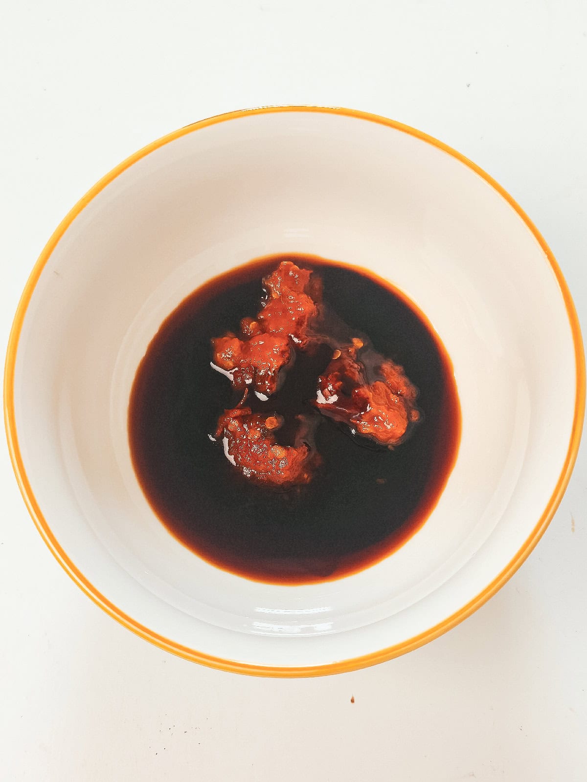 Soy sauce and sambal mixed together in a bowl to make the sauce for vegan nasi goreng.
