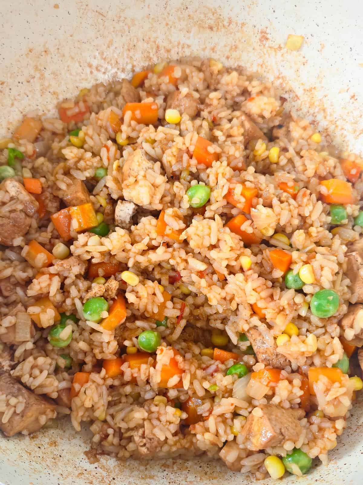 Vegan nasi goreng stirred together in a skillet until the rice is evenly coated with sauce.