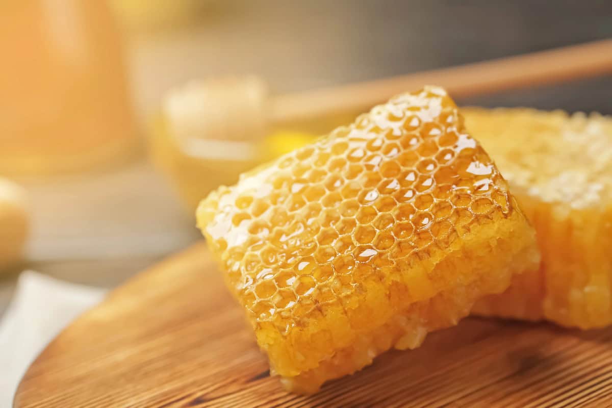 Fresh honeycomb with golden honey on a wooden board.