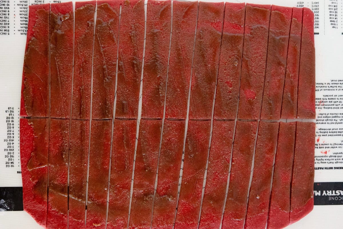 Red velvet cinnamon roll dough topped with cinnamon brown sugar filling and cut into strips.