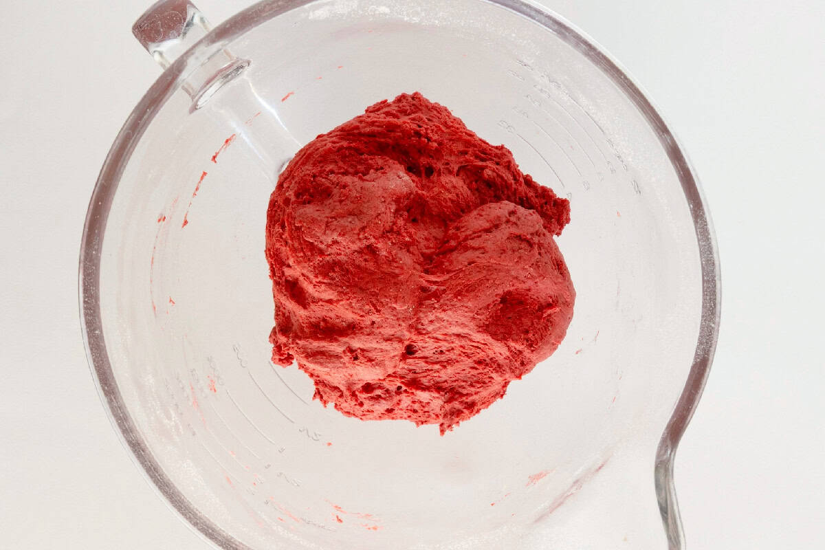 Red velvet cinnamon roll dough mixed and formed in a large mixing bowl.