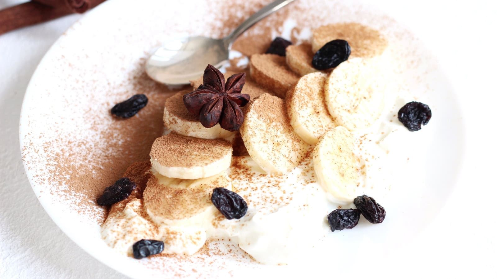 Banana slices with cinnamon, raisins, and star anise on a plate.