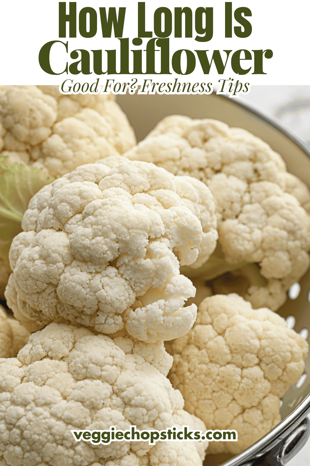 Fresh cauliflower heads resting in a metal colander.