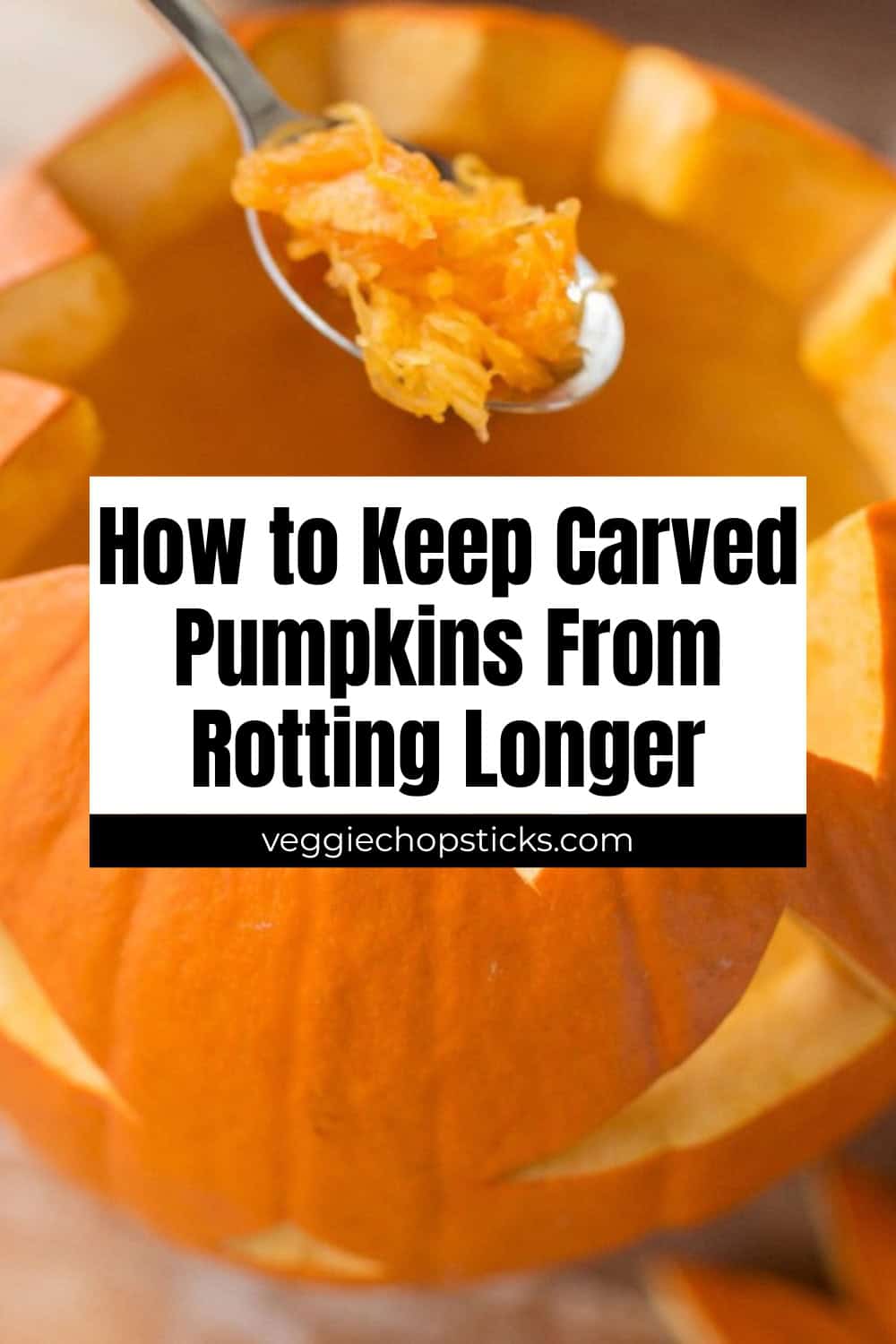 A close-up of a carved pumpkin with a spoon scooping out the stringy pulp.