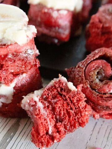 Close-up of red velvet cinnamon rolls showing the soft red interior, cinnamon swirl, and cream cheese frosting.