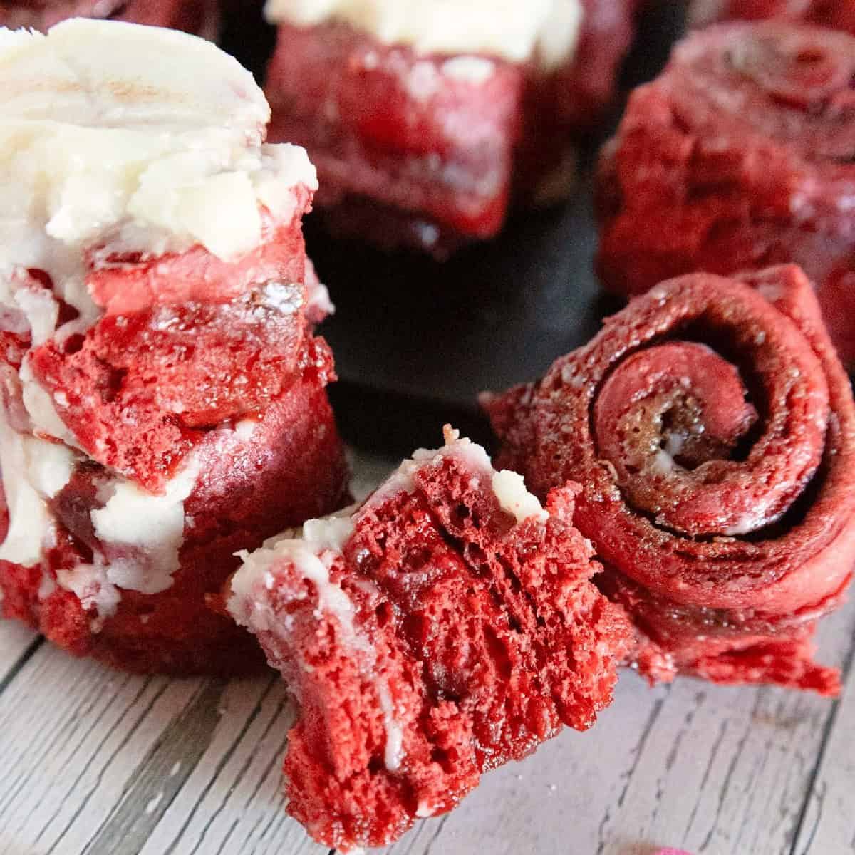 Close-up of red velvet cinnamon rolls showing the soft red interior, cinnamon swirl, and cream cheese frosting.