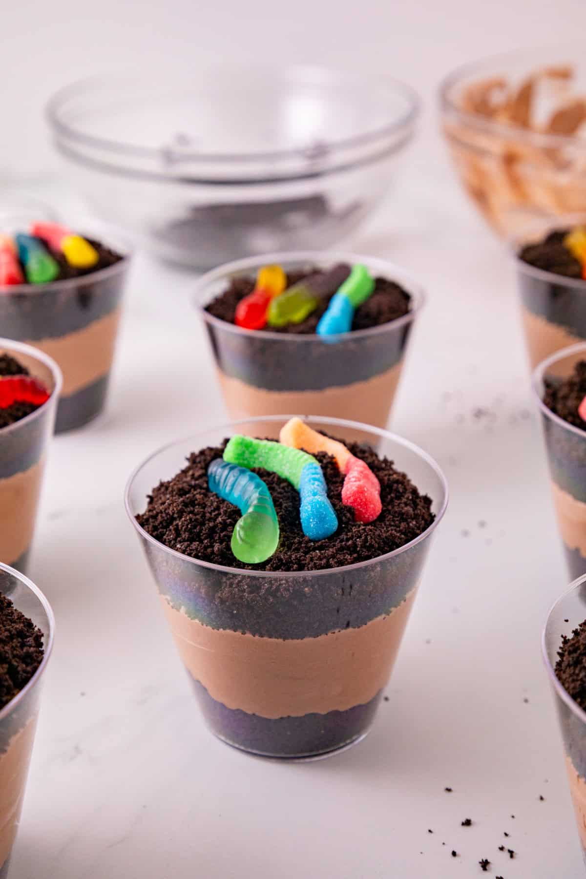 Finished dirt and worms pudding cups layered with chocolate pudding, Oreo crumbs, and gummy worms.