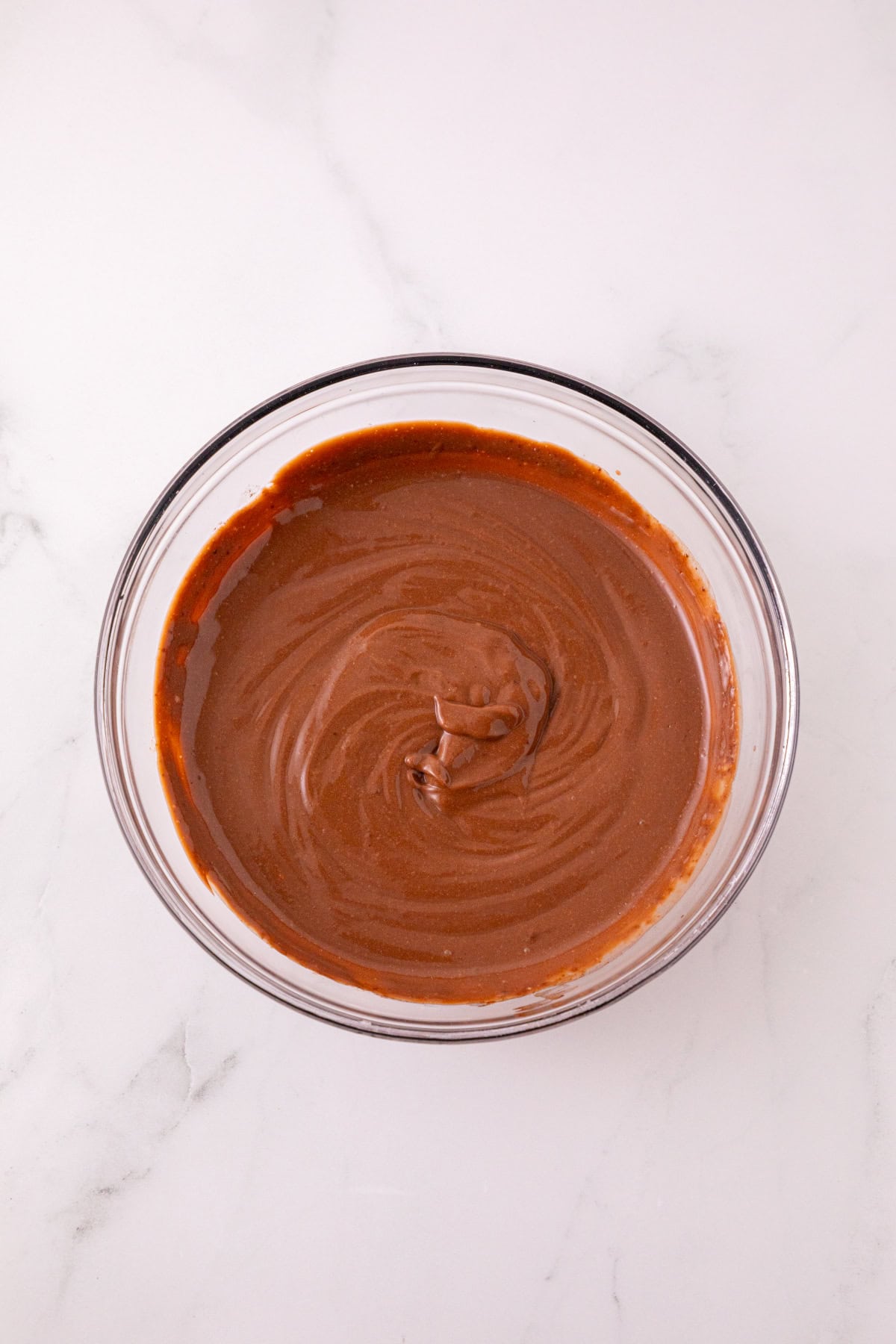 Chocolate pudding mixed with milk in a glass bowl.