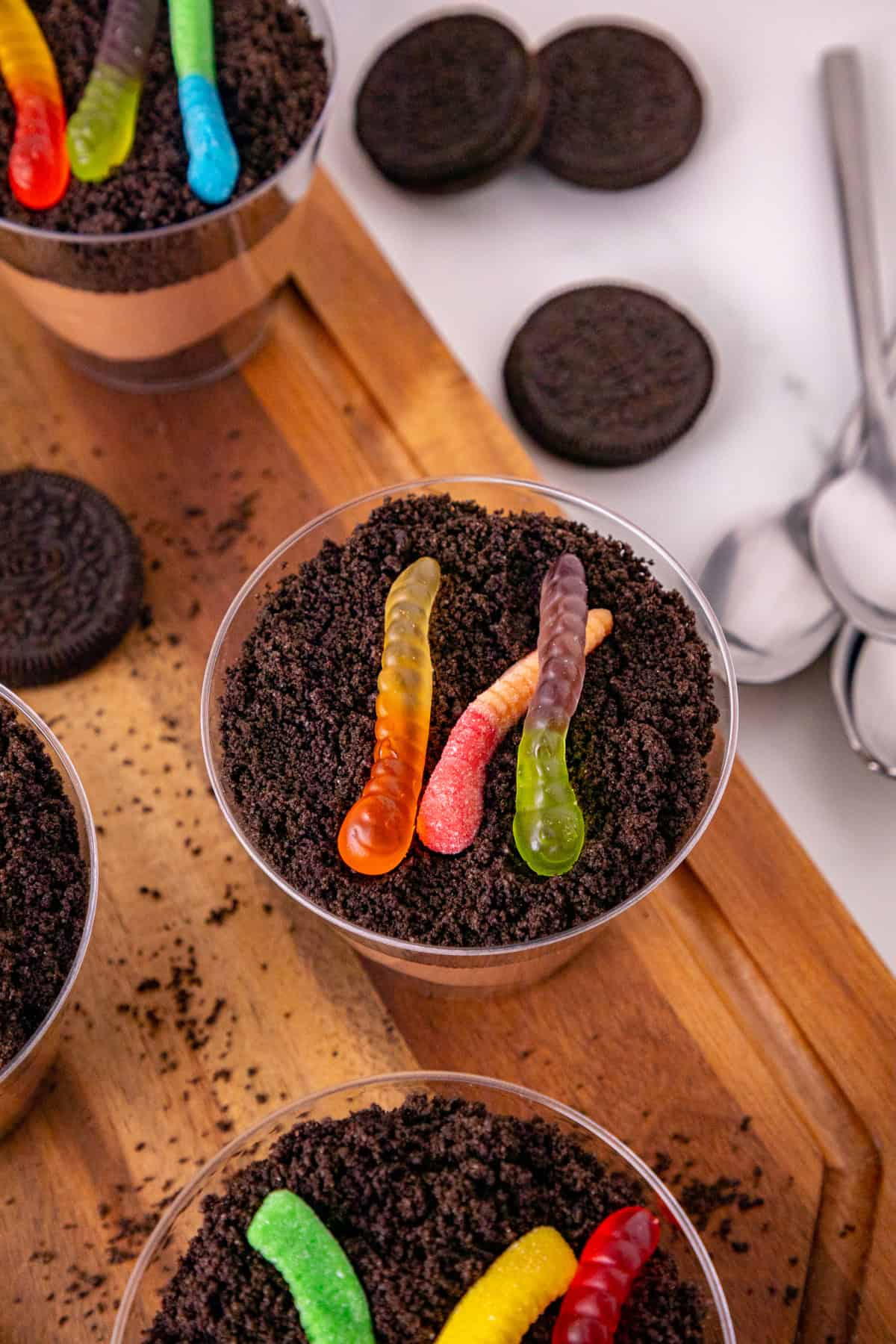 Dirt and worms pudding cup with gummy worms and Oreo crumbs surrounded by Halloween decorations.