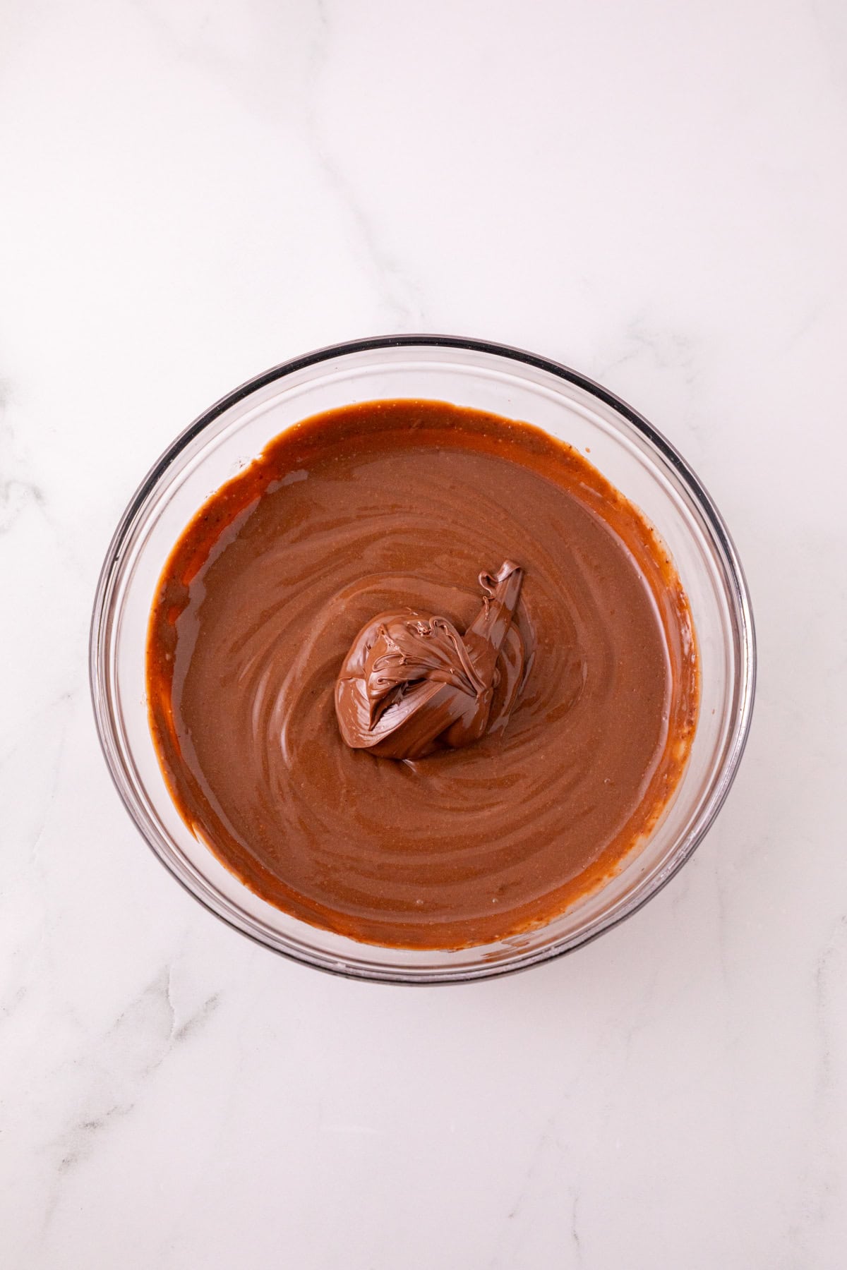 Nutella added to chocolate pudding in a glass mixing bowl.