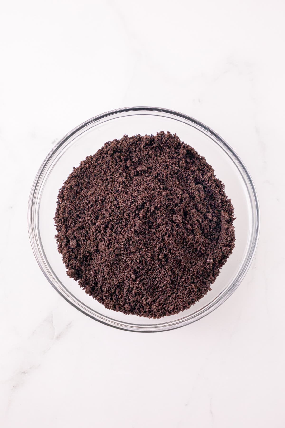 Finely crushed Oreo cookie crumbs in a glass bowl.